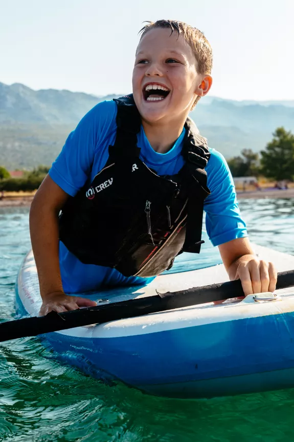 young boy on a paddle board laughing