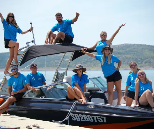 A Neilson waterski instruction team sits on a powerboat moored against the quay