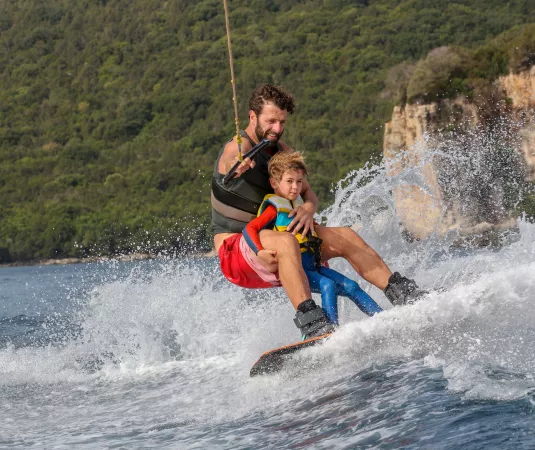 Image shows a man and young boy wakeboarding
