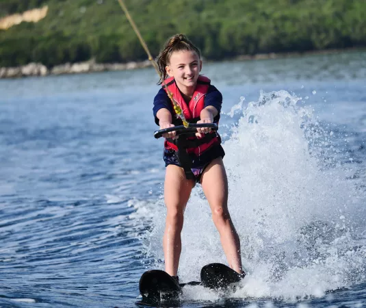 A young girl water skiing confidently