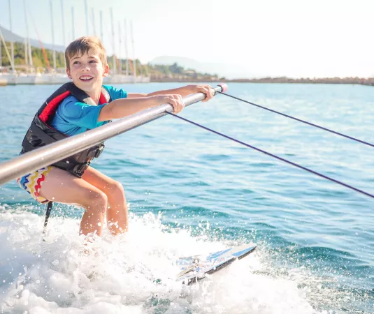A young boy engaged in water skiing on a sunny day.