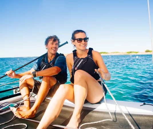 a happy young couple sitting on a small sailboat on a sunny day. 