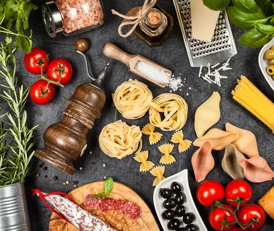 displays an assortment of Italian culinary ingredients on a dark surface. 