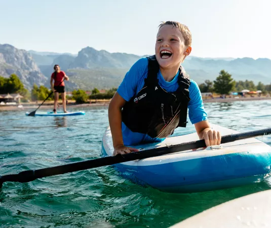 A child enjoying paddleboarding at Alana Beach club