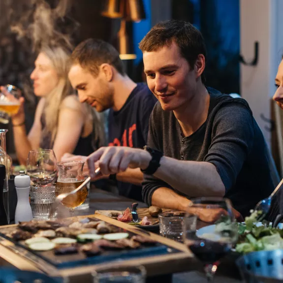 Group of people eating dinner around the table in a ski chalet