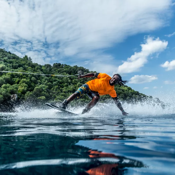 A person wakeboarding on a clear, calm body of water. 