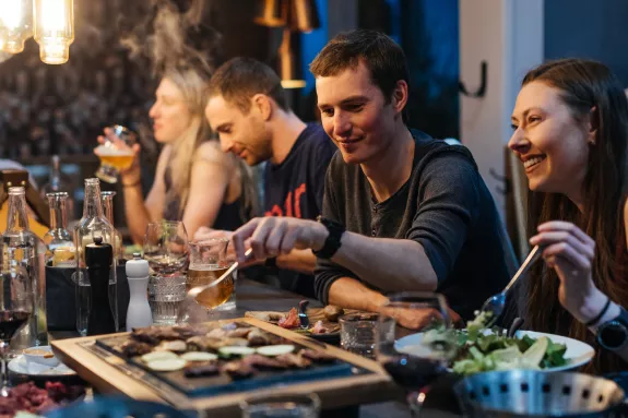 Group of people eating dinner around the table in a ski chalet