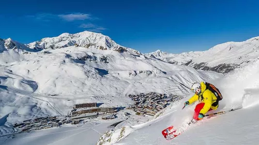 Person Skiing high above village in valley below 