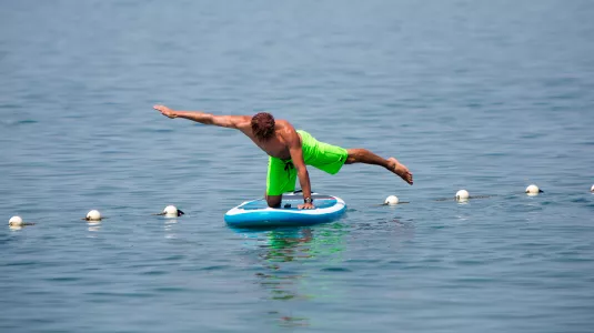 Man doing yoga on stand up paddle board