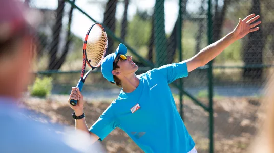 Neilson tennis coach showing how to perform a tennis serve
