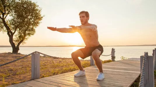 person doing squats on the beach